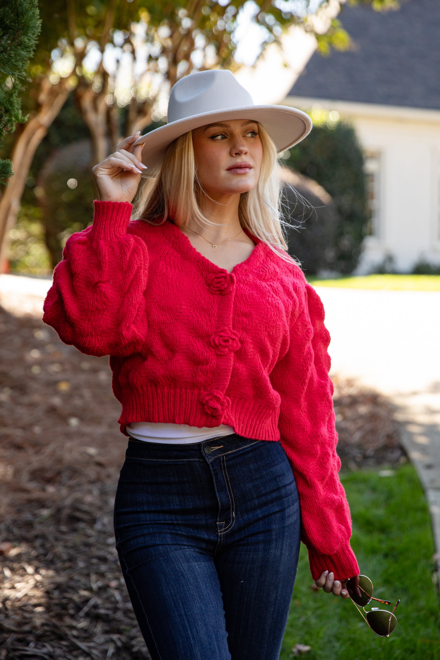 Woman wearing a red cardigan and white hat outdoors