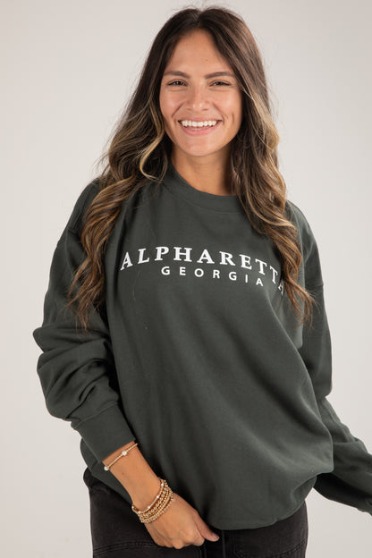 Woman wearing a dark green sweatshirt with &