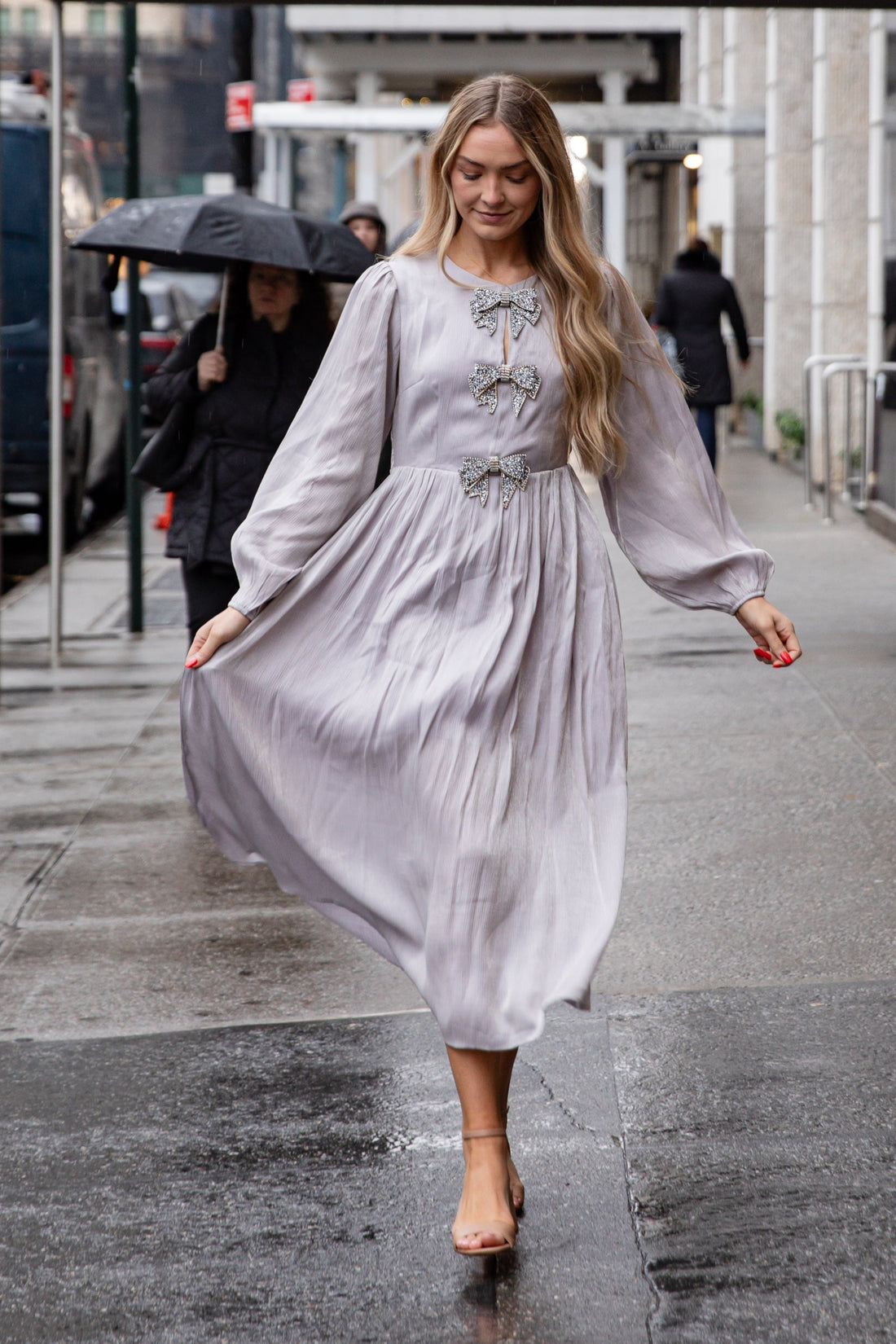 Woman in a light dress walking on a city sidewalk with &
