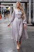 Woman in a light gray dress walking on a city street with &