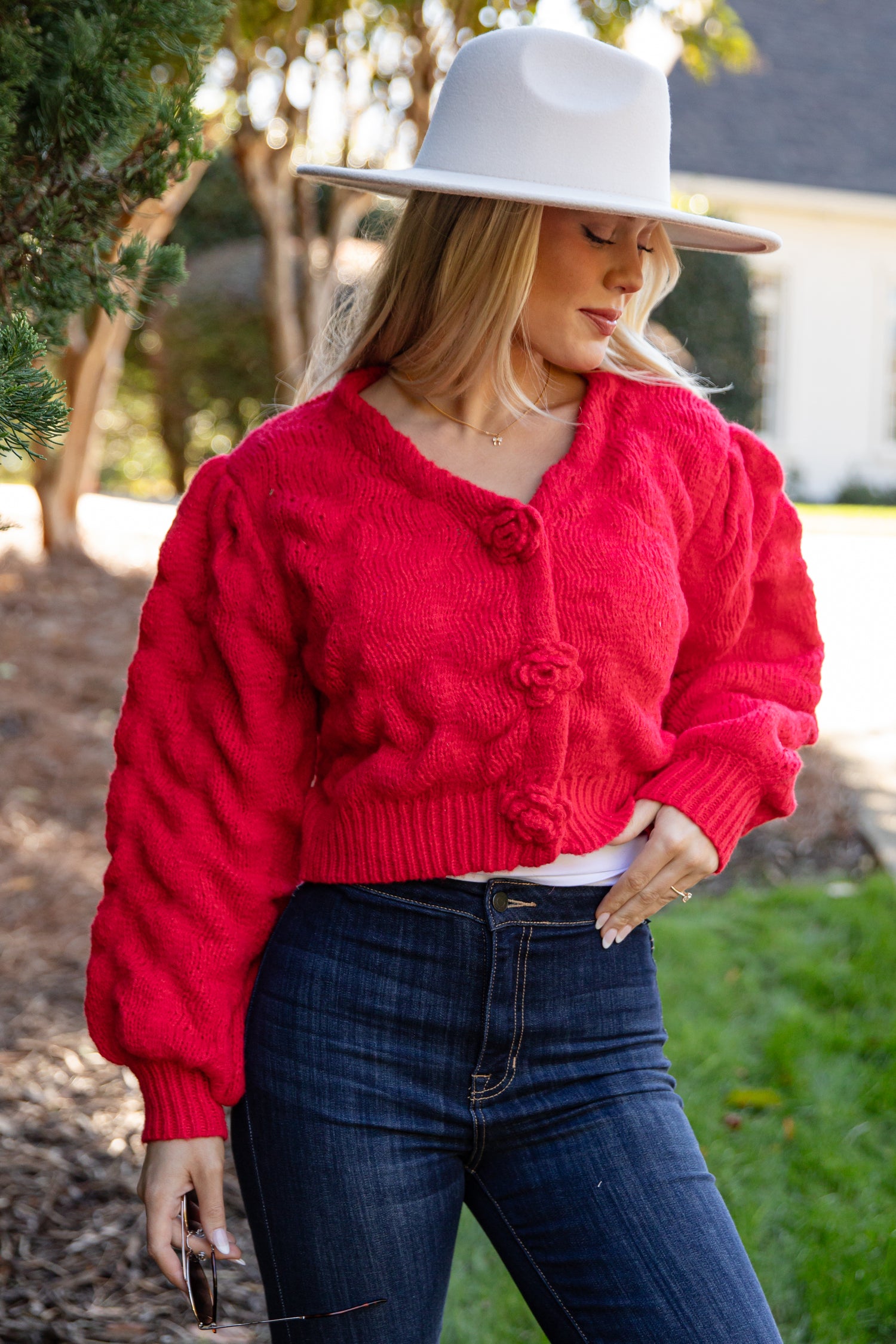 Person wearing a red cardigan and white hat outdoors