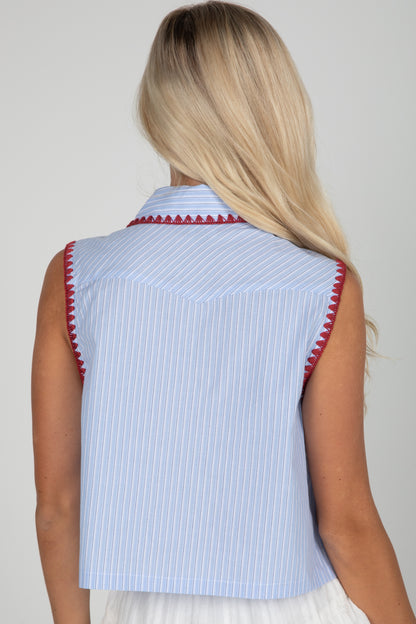 Light blue sleeveless top with red trim worn by a person on a plain background