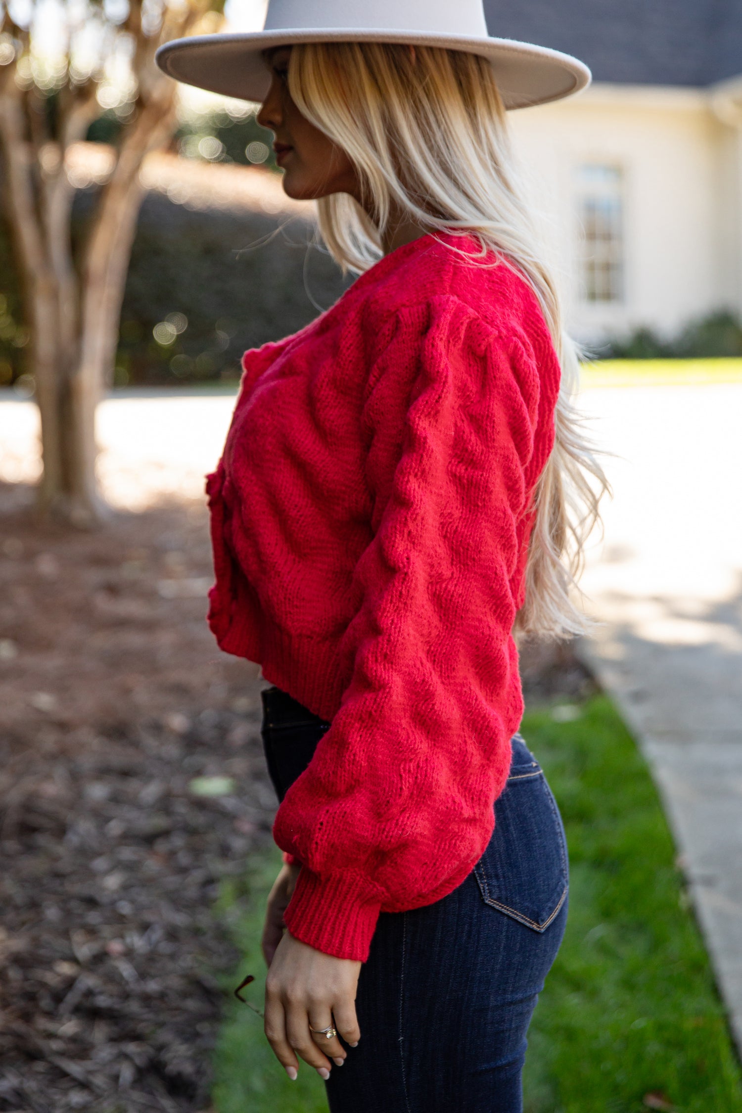 Woman wearing a red sweater and wide-brimmed hat outdoors