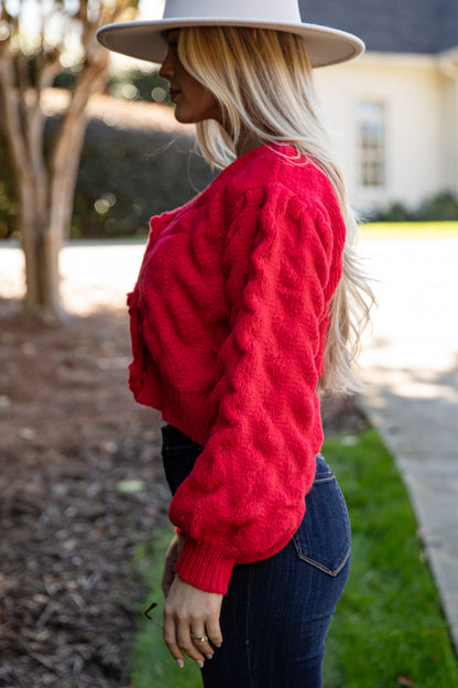 Woman wearing a red sweater and wide-brimmed hat outdoors