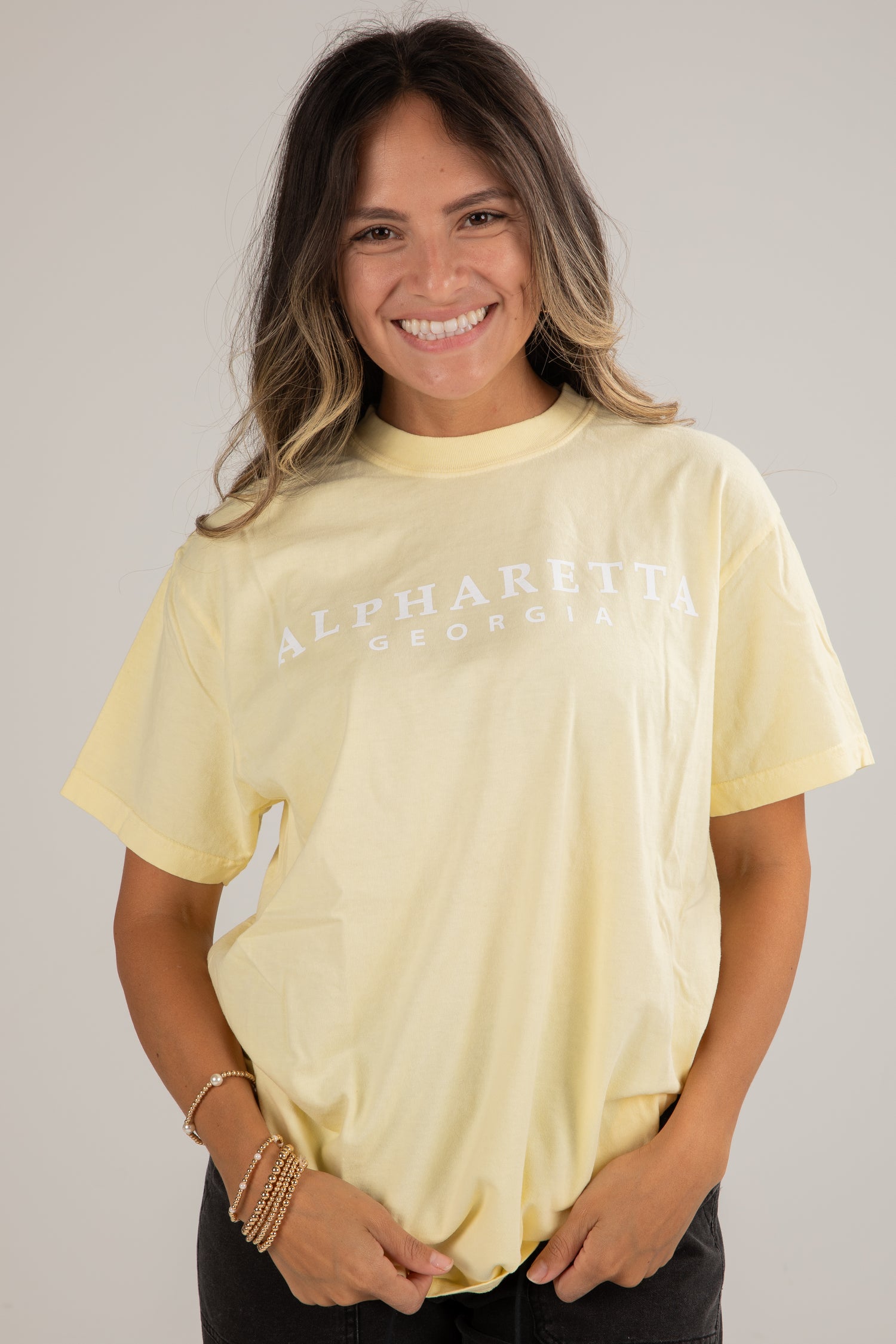 Woman wearing a light yellow t-shirt with text on a plain background