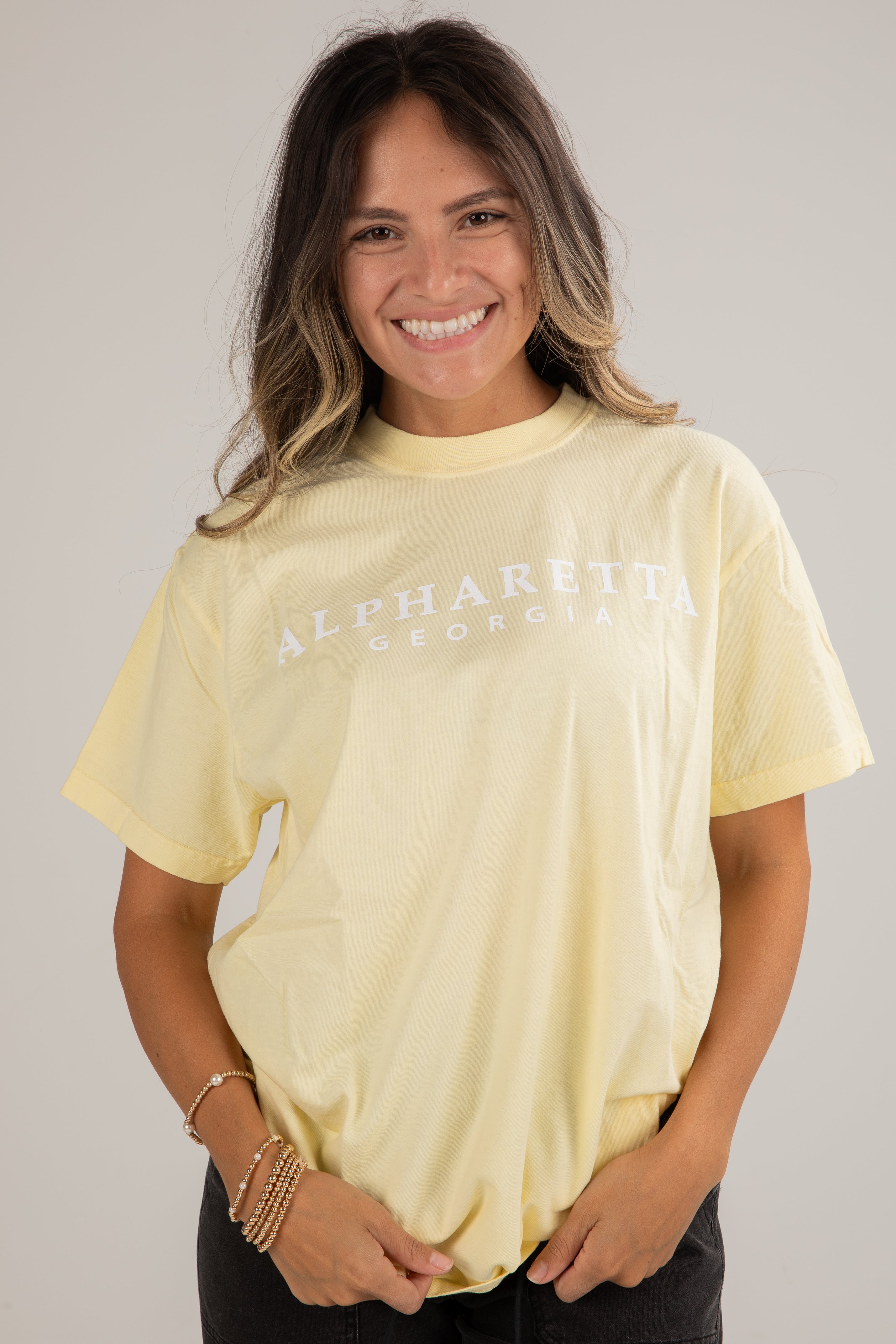 Woman wearing a light yellow t-shirt with text on a plain background