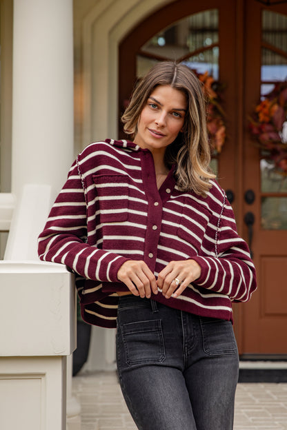Woman wearing a maroon and white striped shirt standing on a porch.