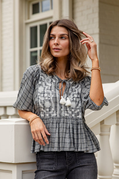 Woman wearing a patterned blouse and jeans standing on a staircase.
