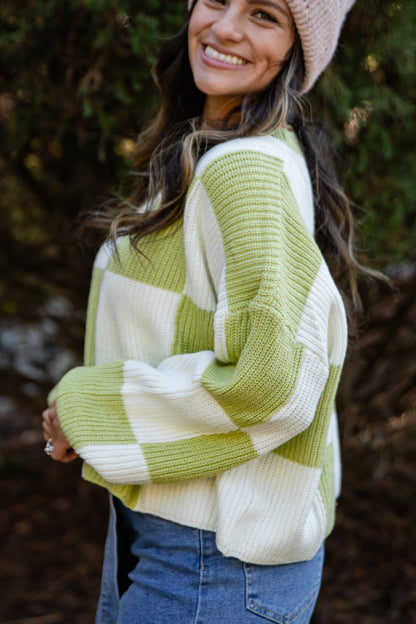 Woman wearing a green and white striped sweater with a blurred natural background