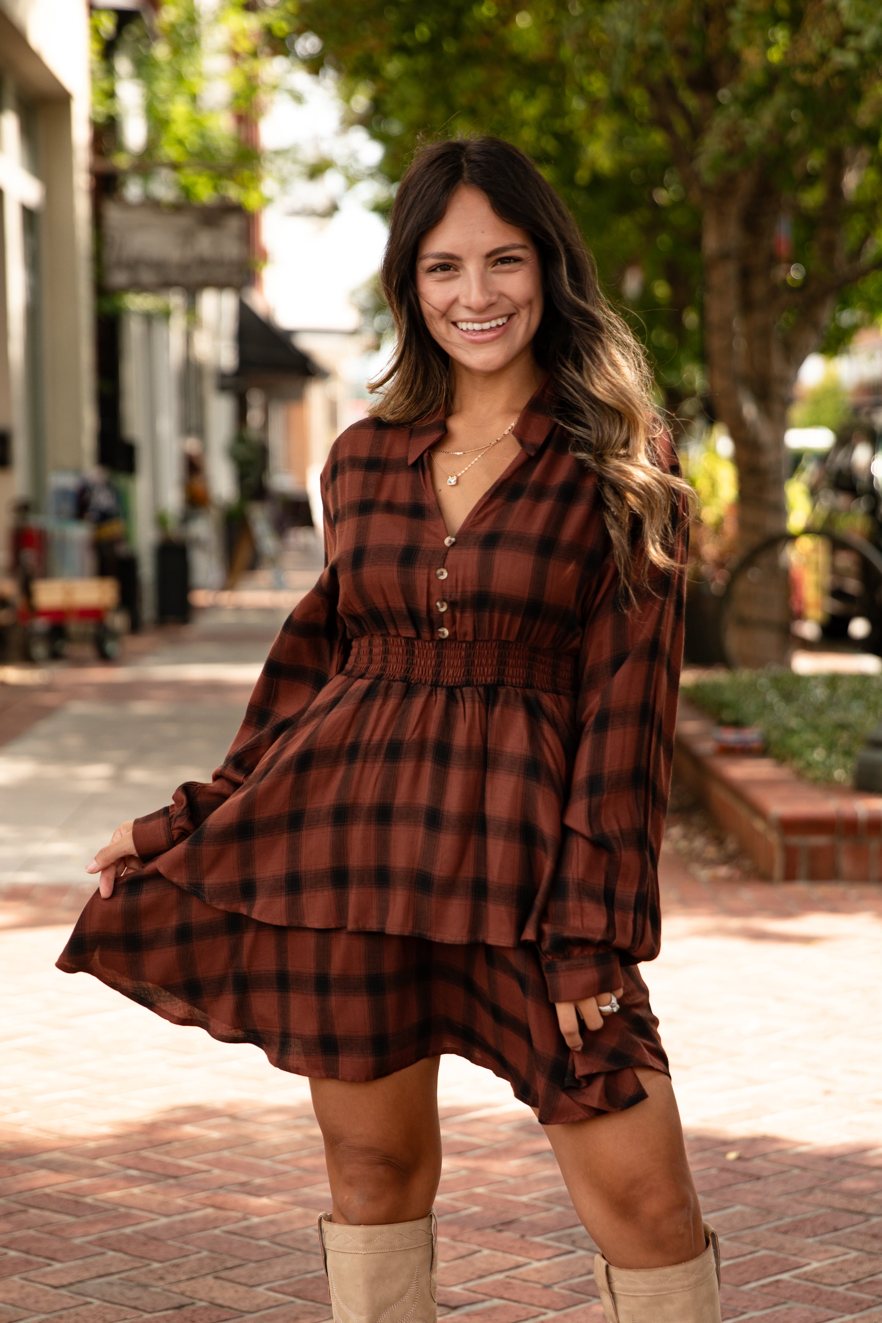 Woman wearing a brown plaid dress with long sleeves in an outdoor setting
