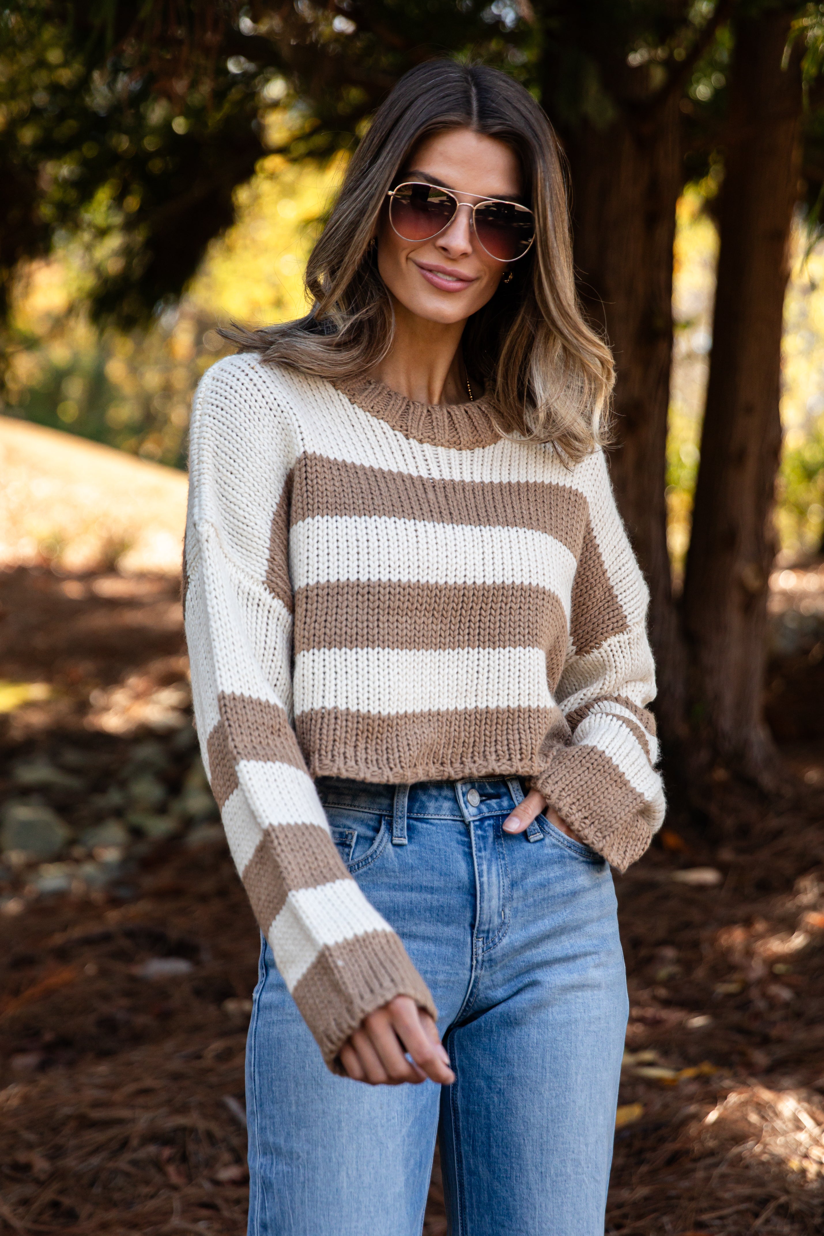 Woman wearing a striped sweater and sunglasses outdoors