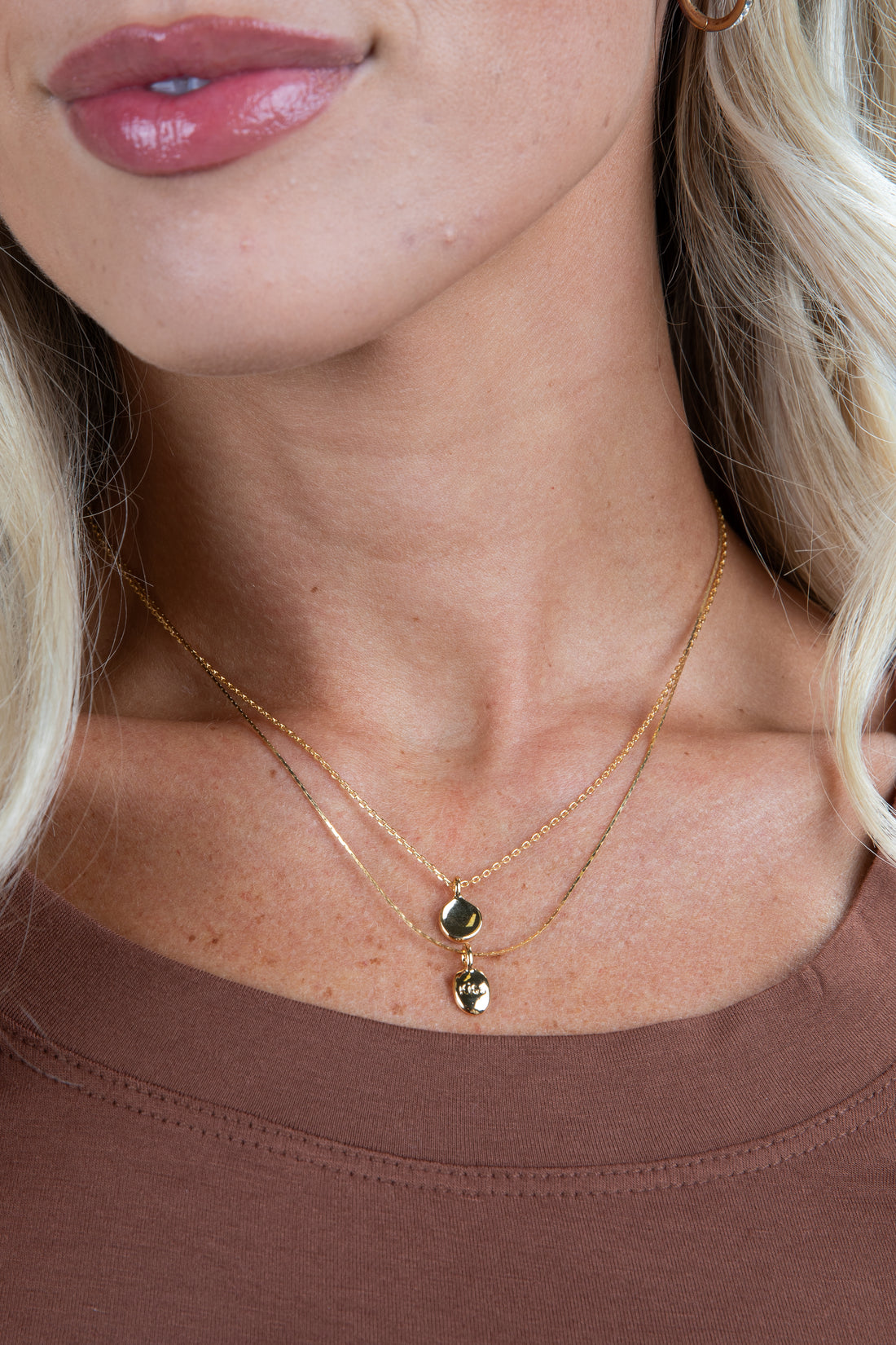 Close-up of a woman wearing a gold necklace with green gemstones.