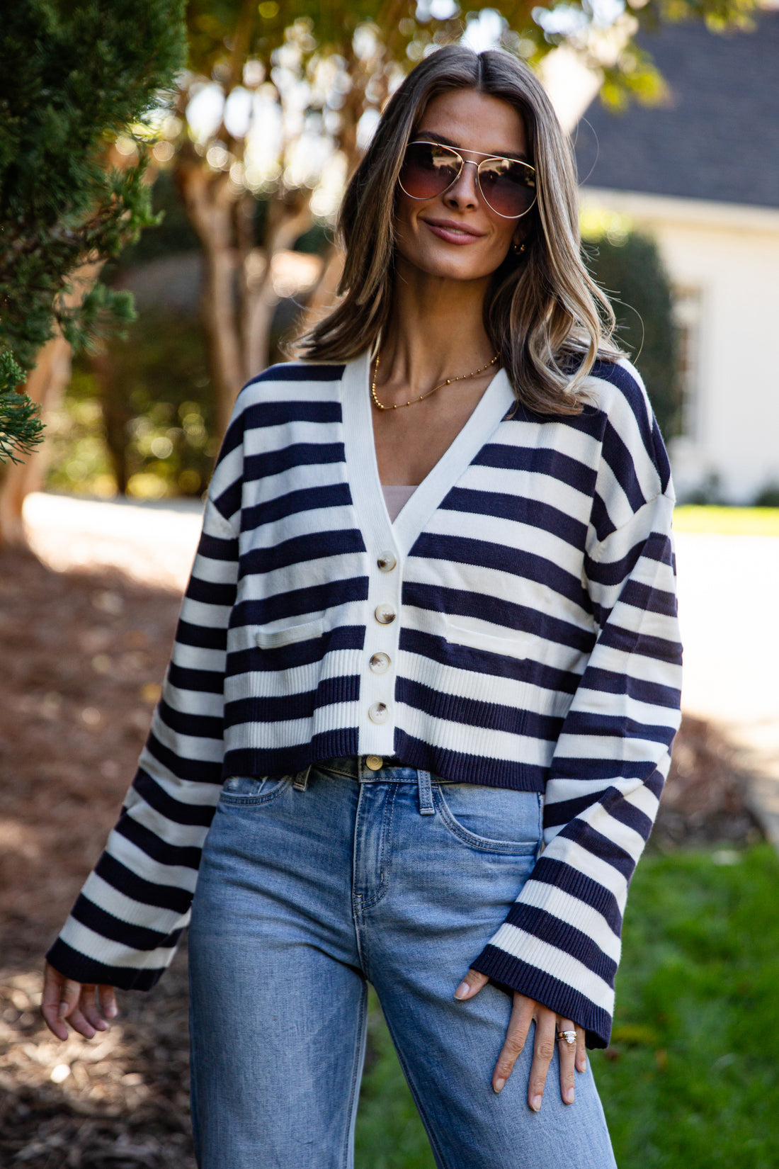 Woman wearing a navy and white striped cardigan with blue jeans outdoors.