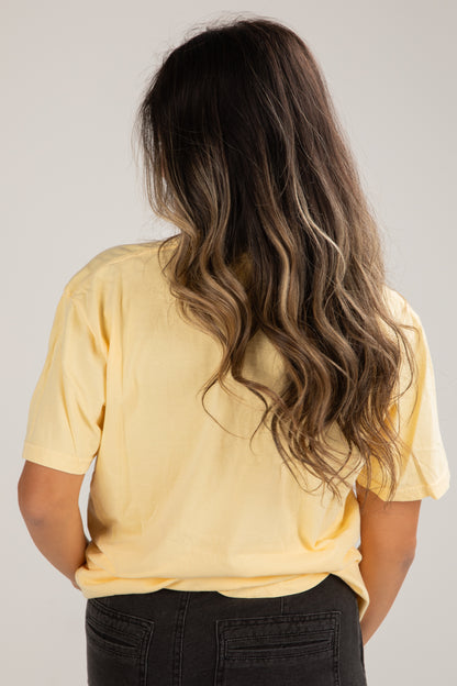 Person wearing a yellow shirt with long, wavy hair on a plain background