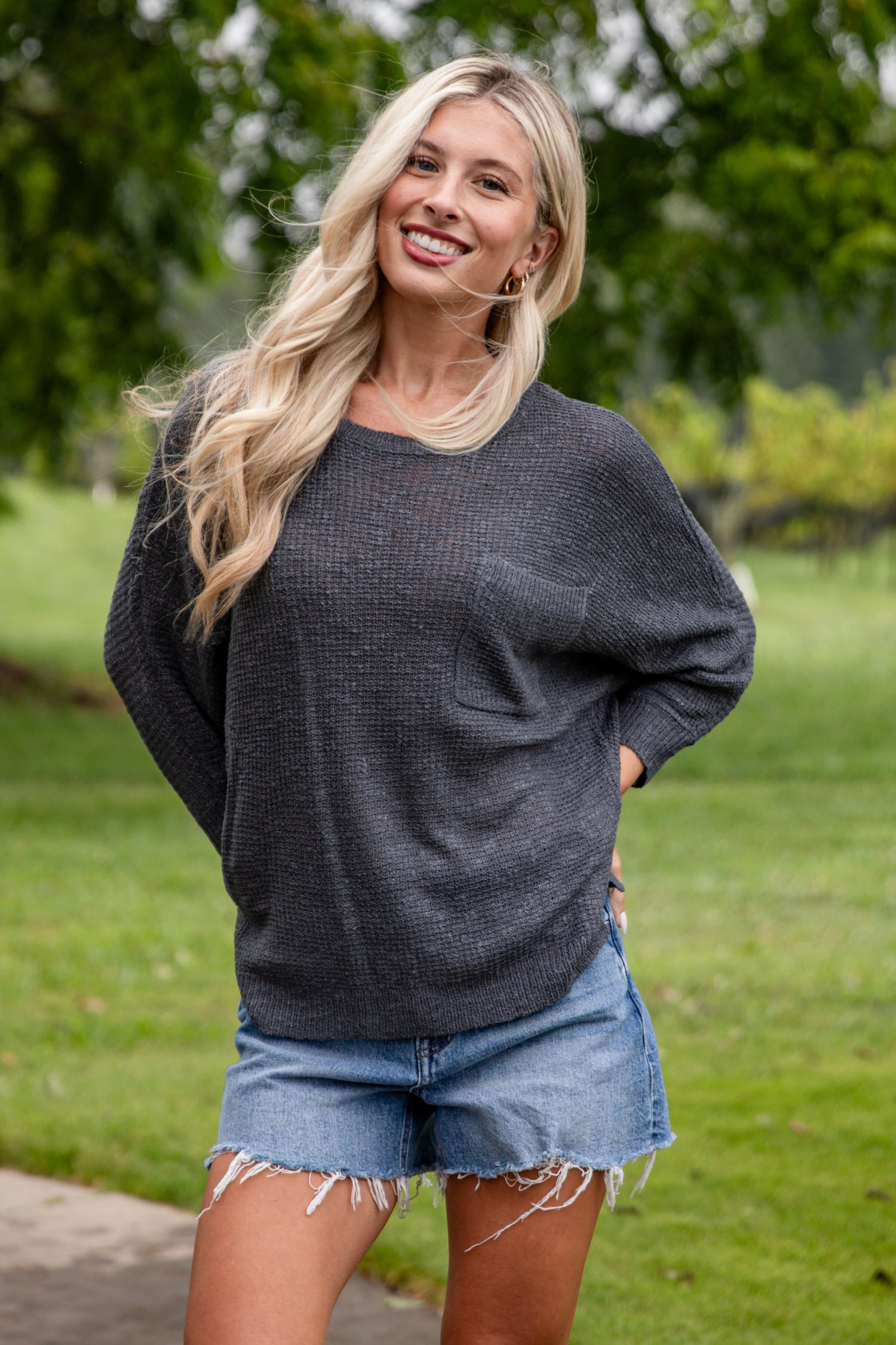 Woman standing outdoors in a casual setting with greenery
