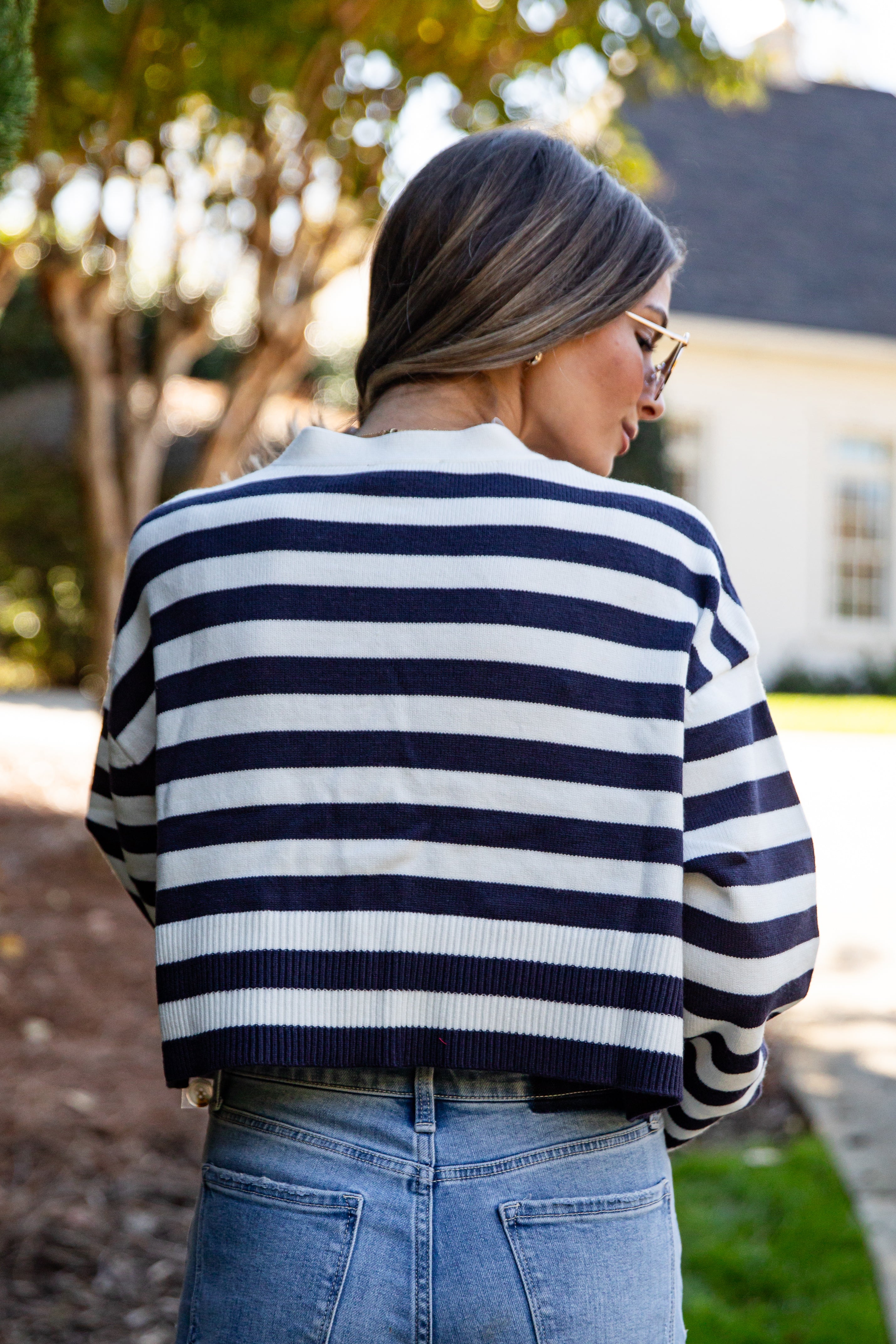 Woman wearing a navy and white striped sweater with blue jeans outdoors.