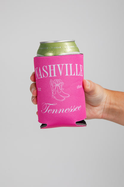 Hand holding a can with a pink Nashville, Tennessee koozie on a gray background