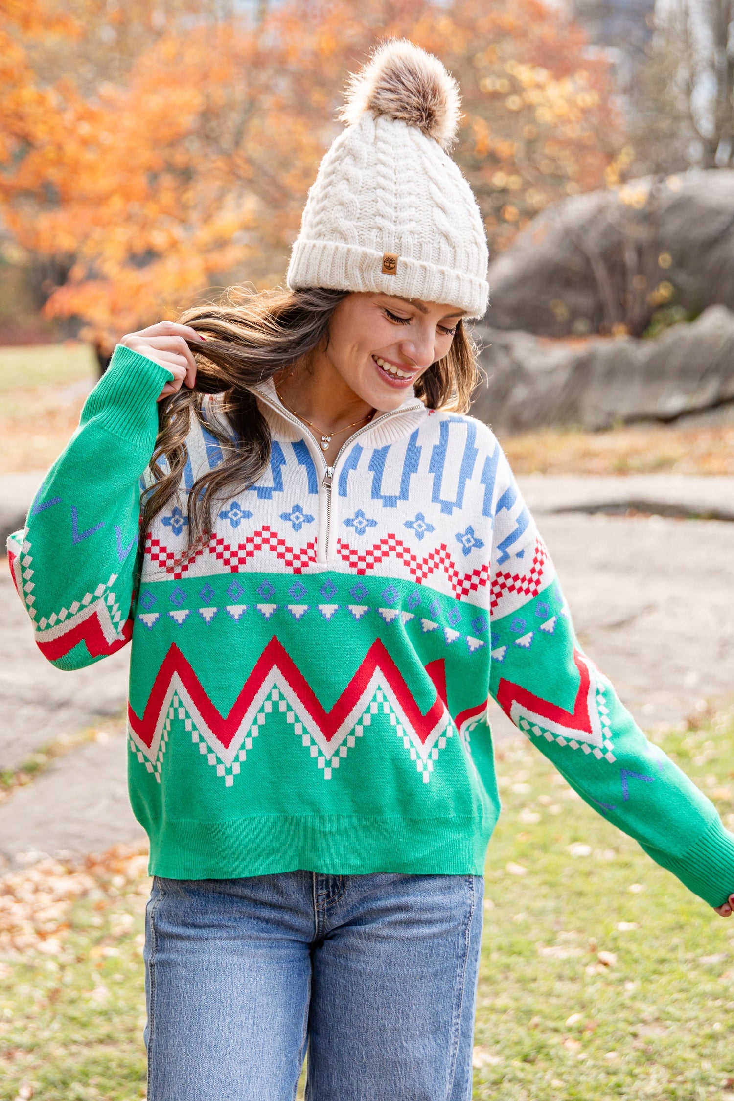 Person wearing a green patterned sweater and beanie in an autumn park setting