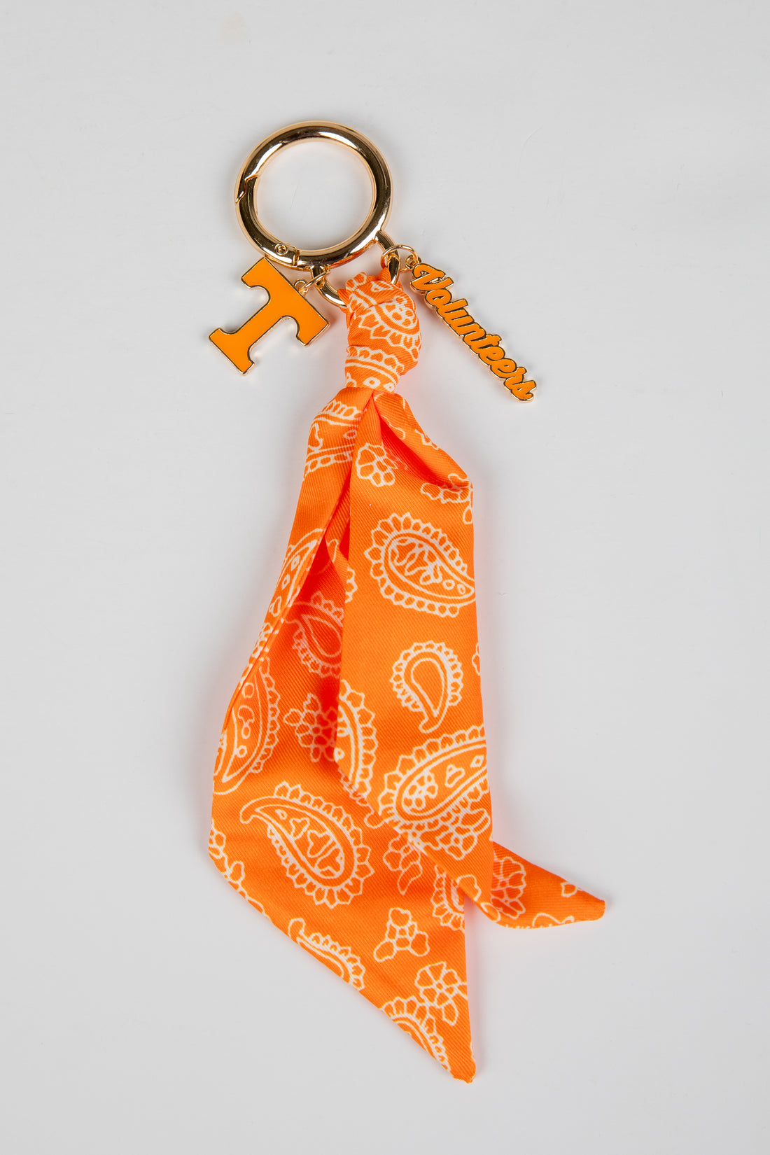 Orange bandana keychain with white patterns on a light gray background