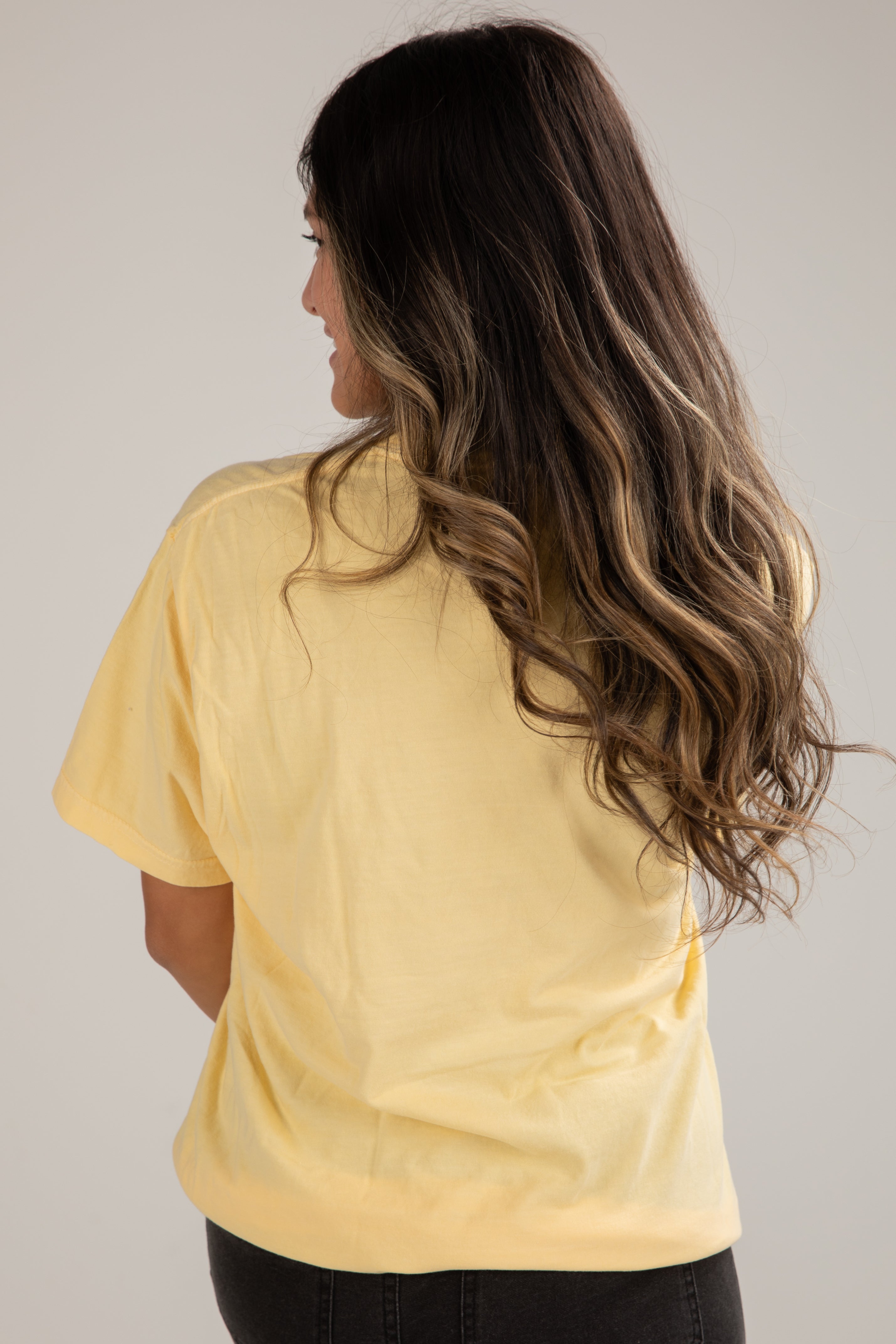 Woman wearing a yellow t-shirt against a plain background