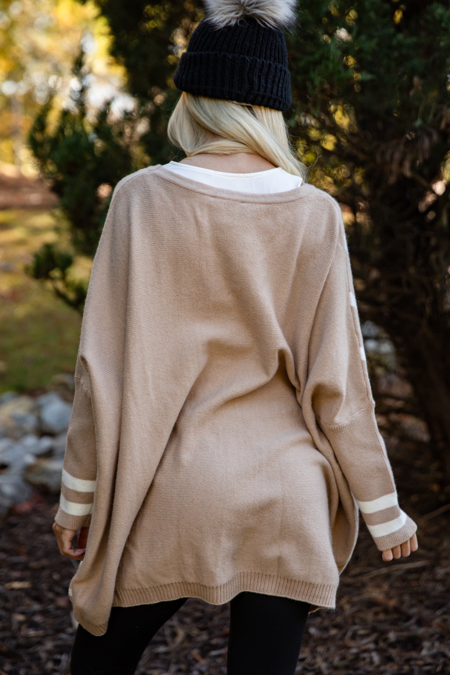 Person wearing a beige cardigan with white stripes in an outdoor setting