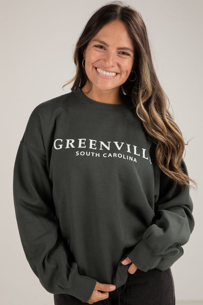 Woman wearing a dark green sweatshirt with &