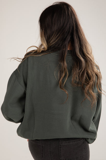 Person wearing a green sweater with long, wavy hair on a plain background