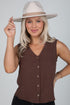 Woman wearing a brown sleeveless top and beige hat against a plain background