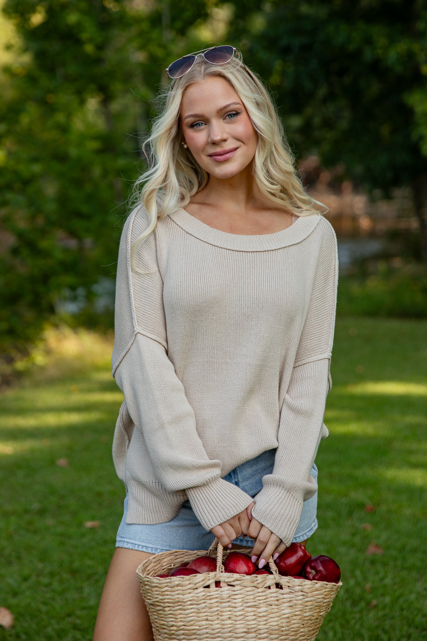 Woman holding a basket of apples in an outdoor setting