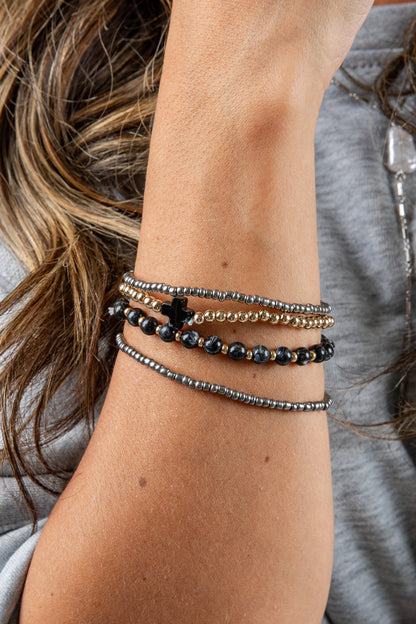 Close-up of a wrist wearing multiple beaded bracelets with a blurred background