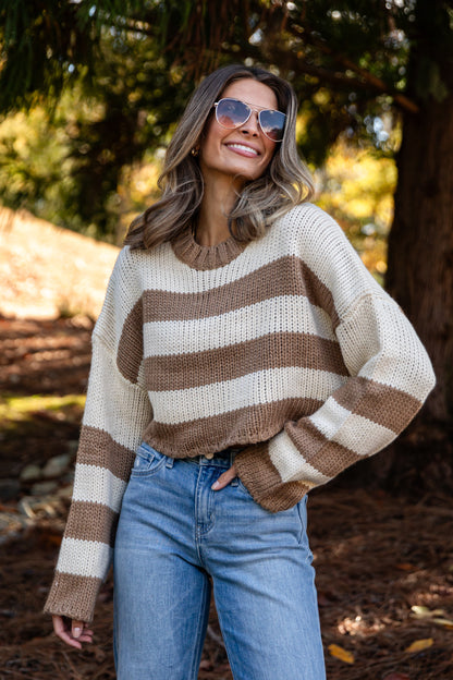 Woman wearing a striped sweater and sunglasses in a forest setting