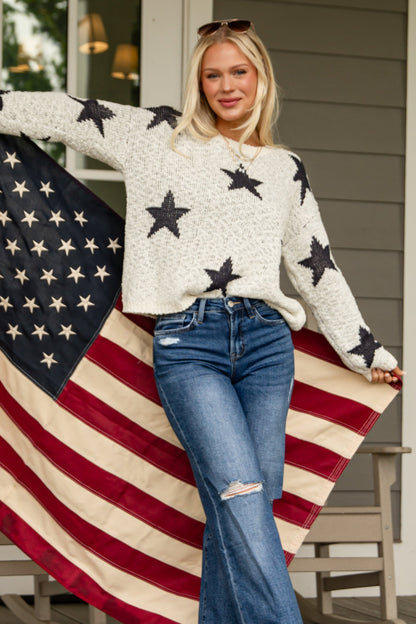Person holding an American flag on a porch