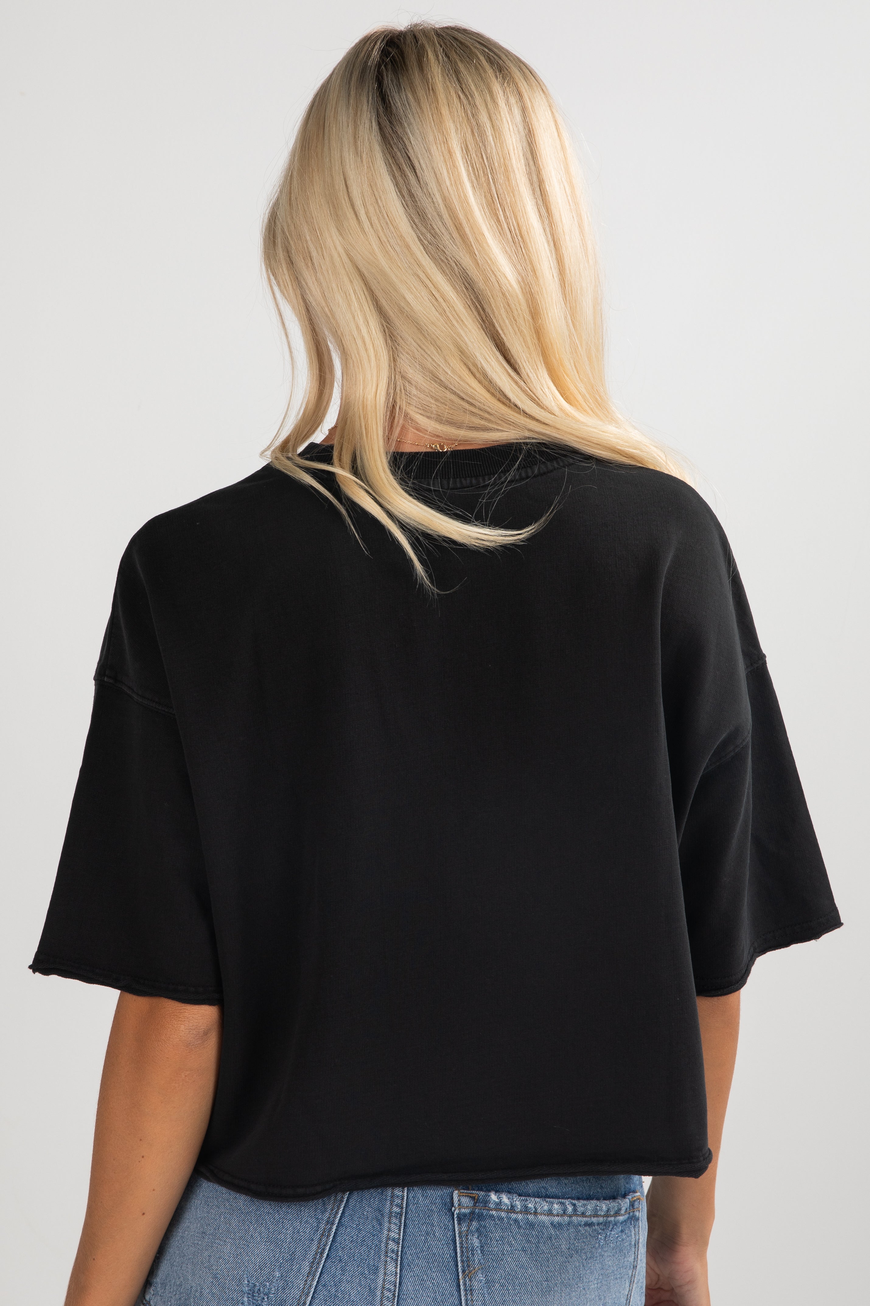 Person wearing a black oversized t-shirt and blue jeans on a white background