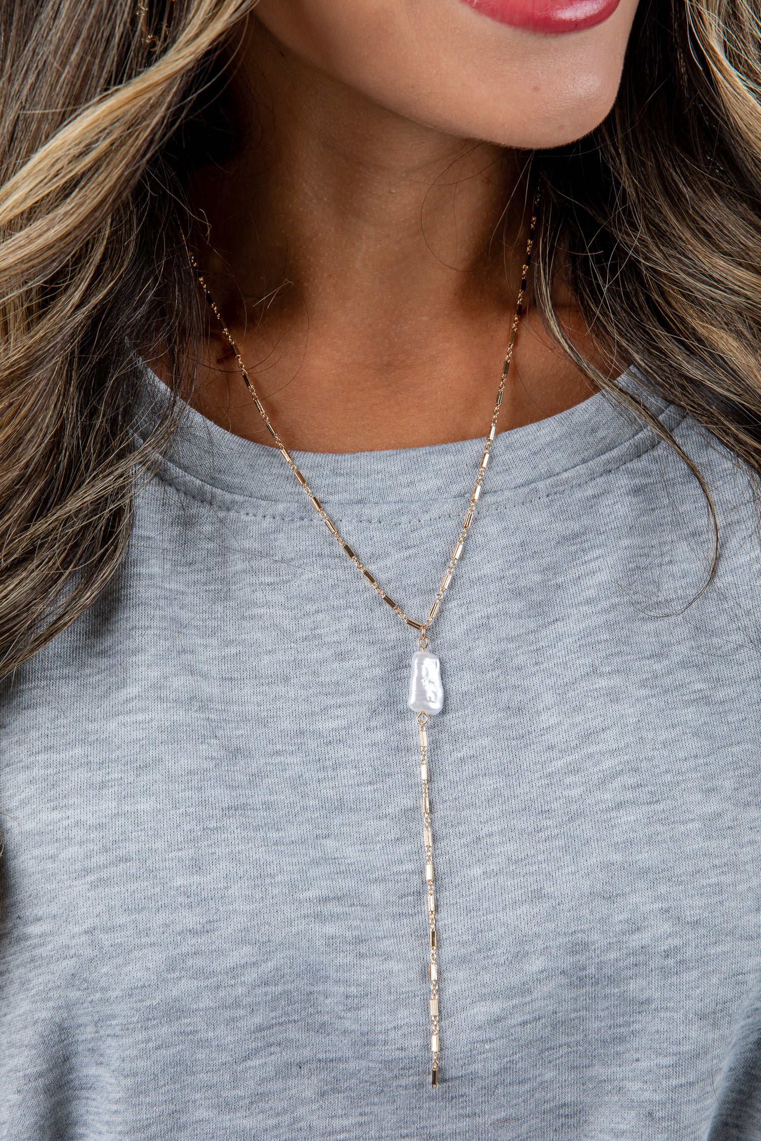 Necklace with a pendant worn by a person against a neutral background