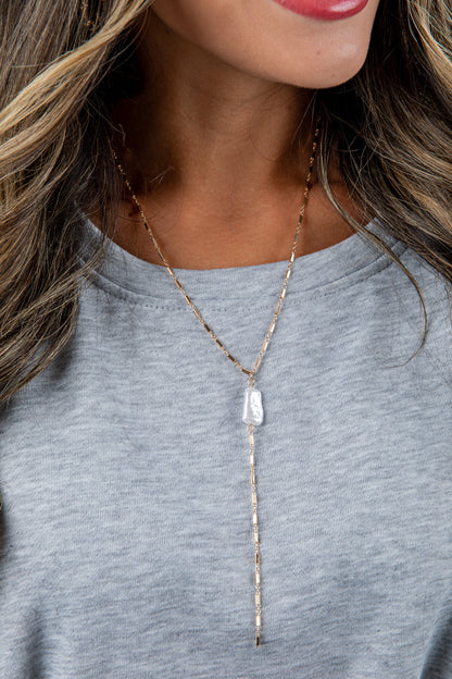 Necklace with a pendant worn by a person against a neutral background