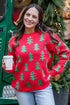 Woman in a red Christmas sweater standing in front of a green truck with a bear inside, holding a coffee cup.