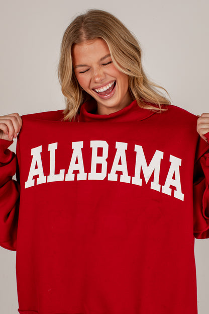 A woman smiling and holding up a red sweatshirt with &