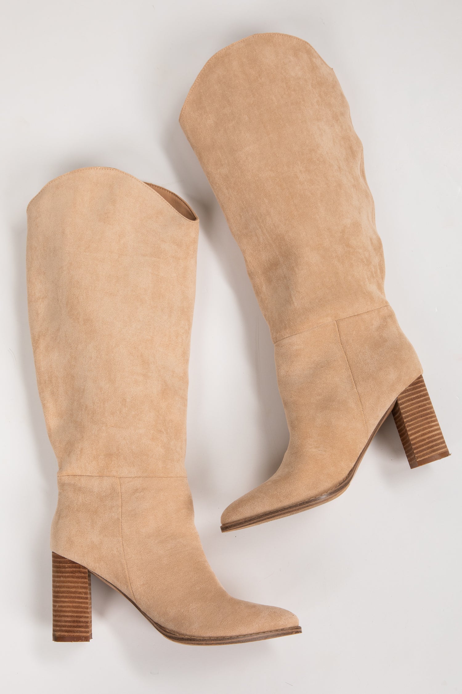 Pair of tan knee-high boots with brown block heels on a light gray background