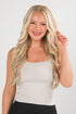Woman with long blonde hair wearing a white top against a plain background