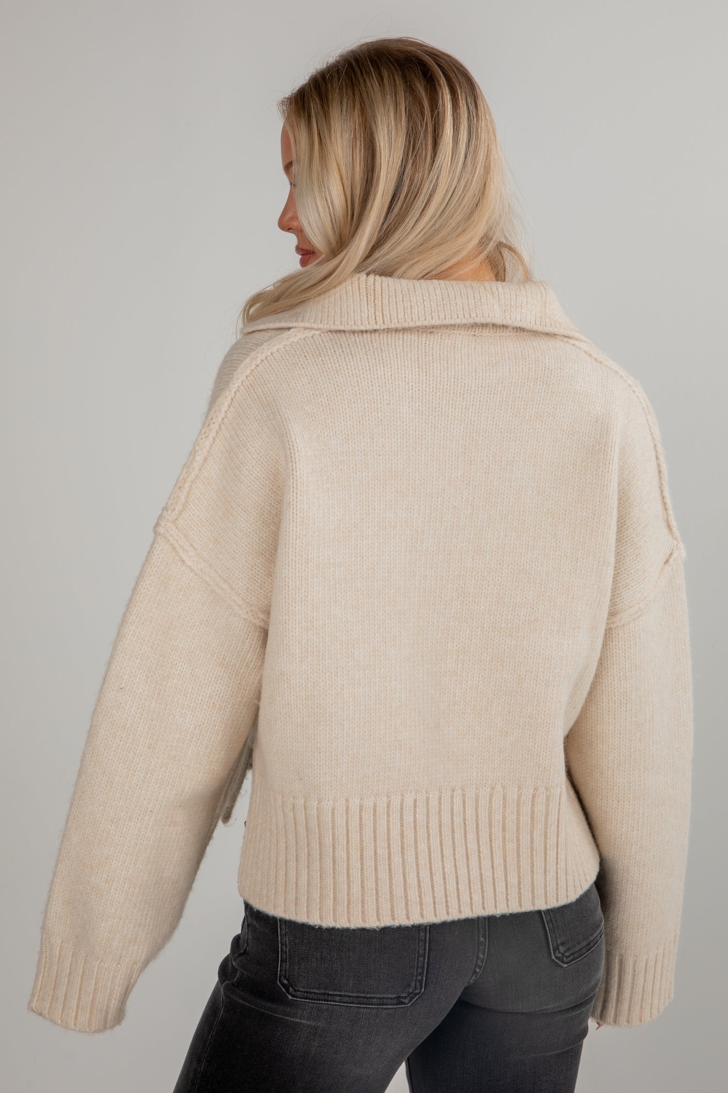 Woman wearing a beige knitted cardigan against a plain background