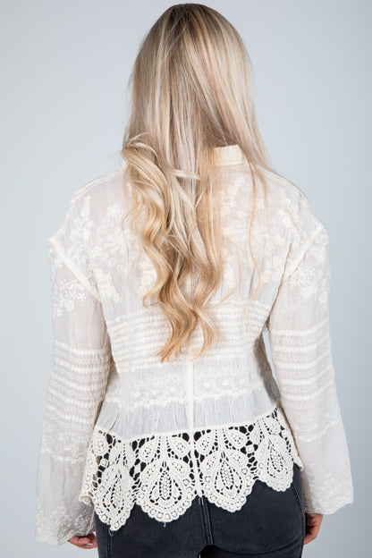 White lace top worn by a person with long blonde hair on a plain background