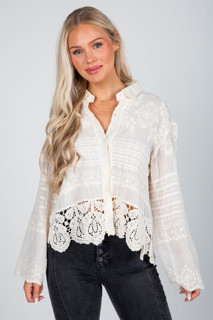 Woman wearing a white lace blouse with black pants on a gray background