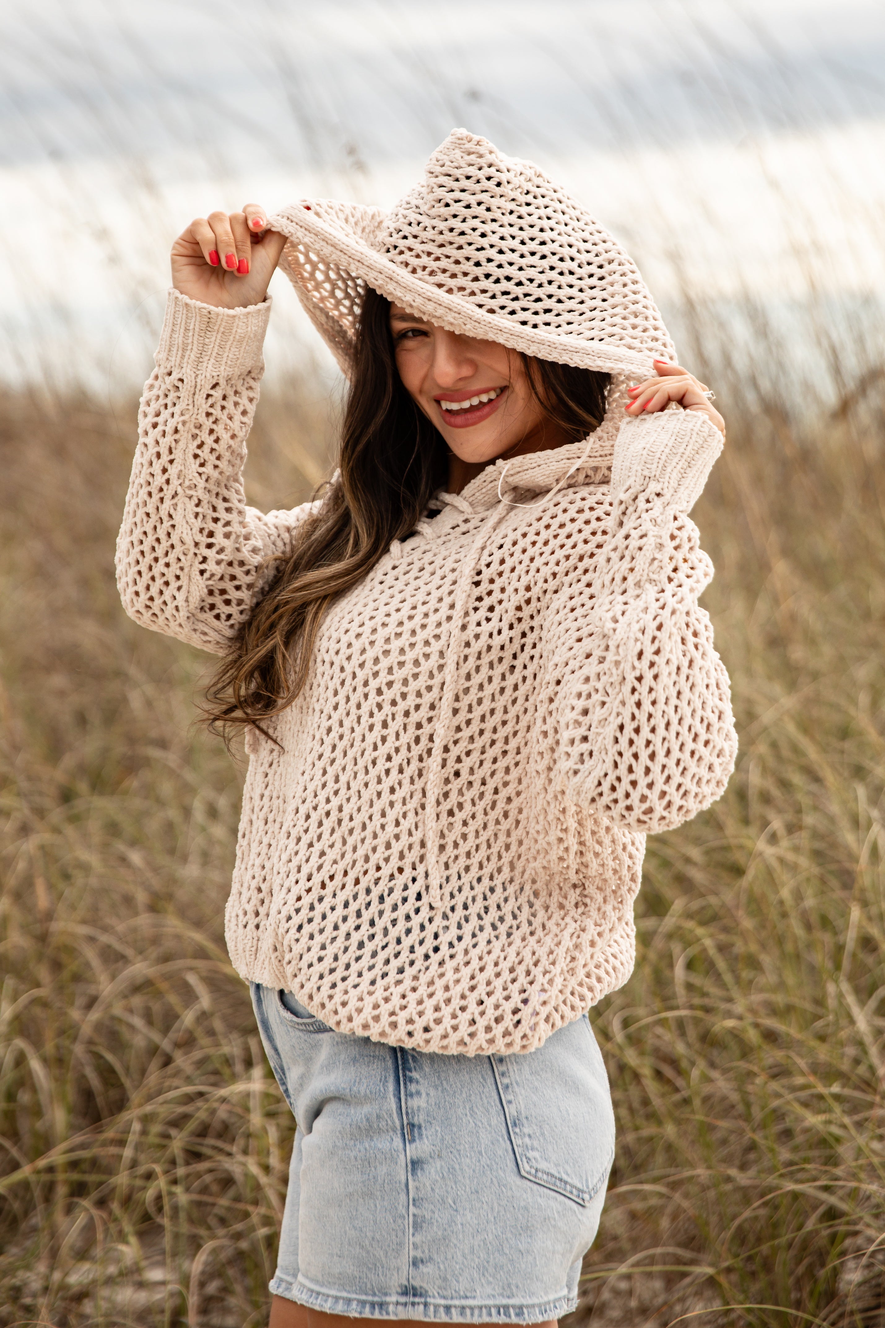 Woman wearing a beige knitted sweater and wide-brimmed hat in a field