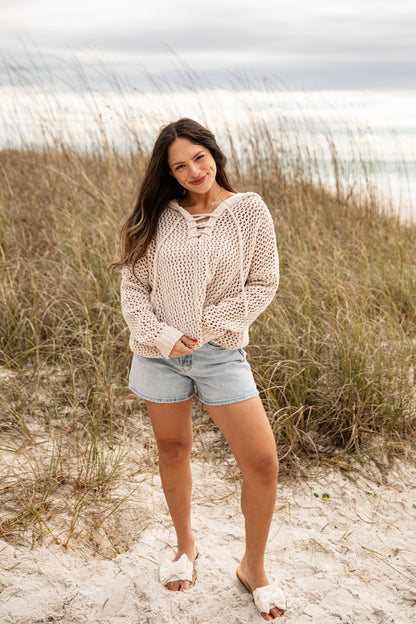 Woman standing on a sandy beach with grassy dunes and ocean in the background