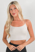 Woman wearing a white tank top against a plain background