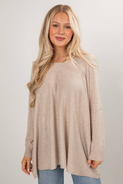 Woman wearing a beige long-sleeve top against a plain background