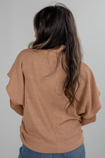 Person wearing a brown sweater with long hair on a plain background