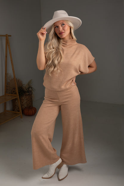 Woman wearing a beige outfit with a hat in a studio setting