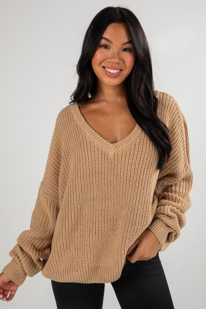 Woman wearing a beige knitted sweater against a white background