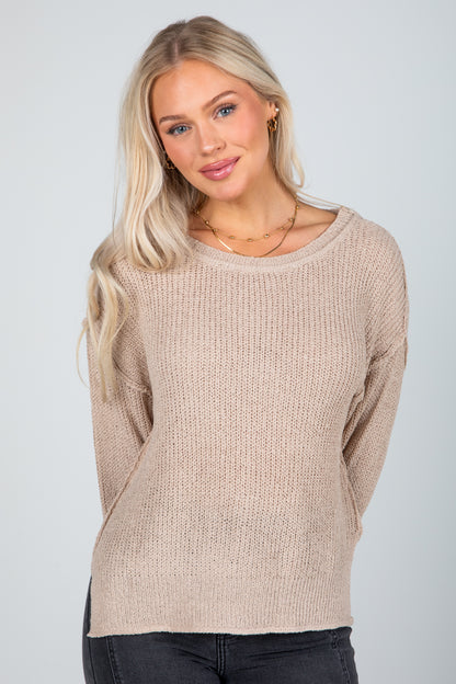 Woman wearing a beige sweater against a plain background